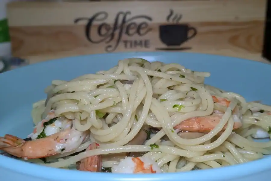 Pasta with Shrimps and Mushrooms in Olive Oil served on a blue plate.